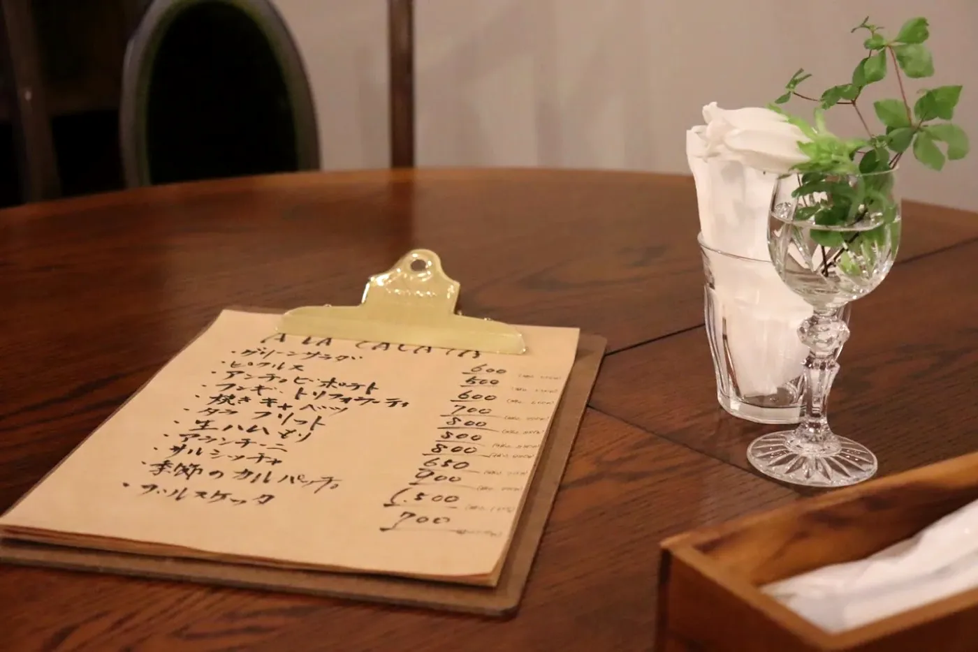 テーブルに置かれた手書きの品書きとグラスの白い花